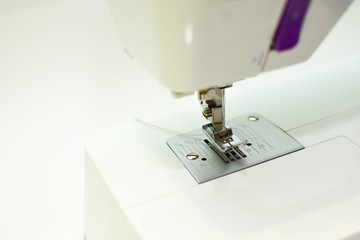 thread tucked into a needle from a sewing machine