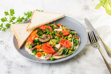 Omelet with vagetable, tomatoes, mushrooms,green beans, corn, sourdough toast isolated on white marble background. Homemade food. Tasty breakfast. Selective focus. Hotizontal photo.
