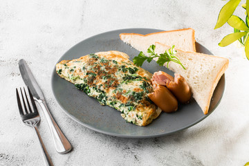 Omelet with spinach, sausages and sourdough toast isolated on white marble background. Homemade food. Tasty breakfast. Selective focus. Hotizontal photo.