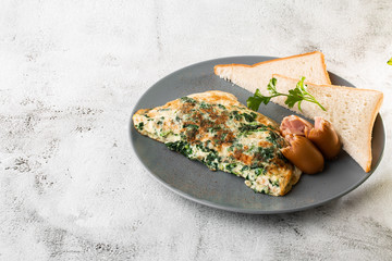 Omelet with spinach, sausages and sourdough toast isolated on white marble background. Homemade food. Tasty breakfast. Selective focus. Hotizontal photo.