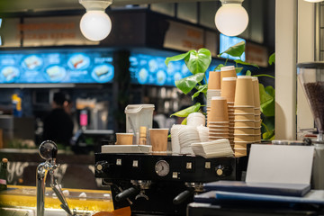 View of a professional coffee machine and paper cups in a coffee shop. The working environment of the cafe. Cafeteria equipment.
