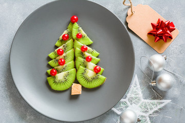 Kiwi Christmas tree with currants, funny food for kids. Christmas food background.