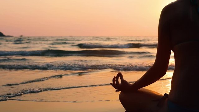 yoga and relaxation on the beach, meditation, unrecognizable person doing breathing exercises at sunset
