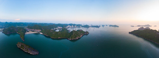 Aerial unique view Vietnam Cat Ba bay with floating fishing boats on sea, cloudscape tropical weather inspirational sunset, epic city skyline and skyscraper, scenic green mountain.