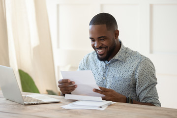 Smiling biracial male receive good news in postal correspondence
