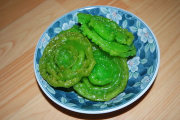 Crispy sweet Asian dessert green Jalebi cooked and served in ceramic plate.