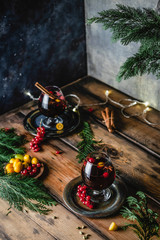 mulled wine in glasses with anise, citrus and berries on brown wooden table, Christmas decoration, copy space