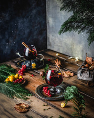 mulled wine in glasses with anise, citrus and berries on brown wooden table, Christmas decoration, copy space