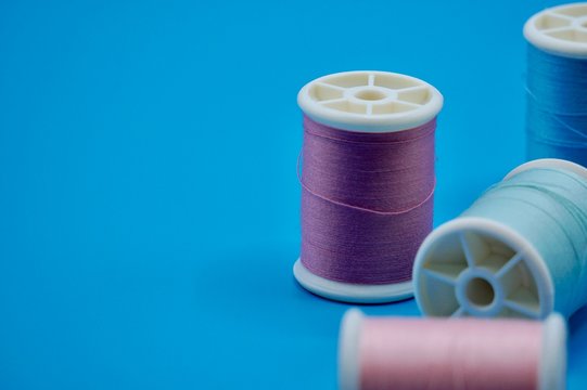A group of purple, green, pink and blue thread on the blue background