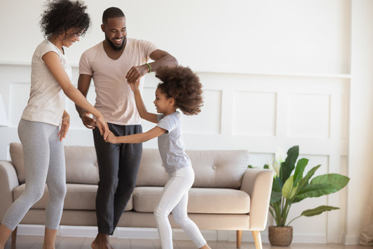 Happy biracial family with kid dancing at home