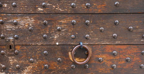 Medieval castle gate. Ancient wooden door with round door knobs and with metal forging.