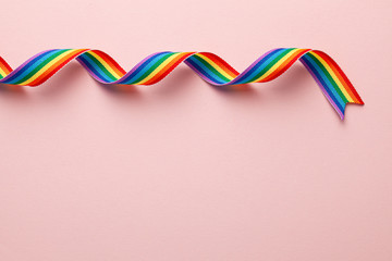 LGBT rainbow ribbon pride tape symbol. Pink background. Copy space for text.