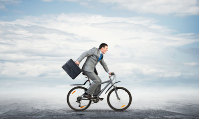 Man wearing business suit riding bicycle outdoor.