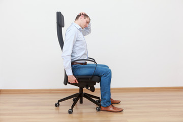 Caucasian man, sitting on office chair, stretching neck - profile