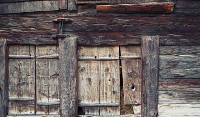 Weathered old wooden shutters window in old vintage barn in Swiss Alps. Timber wood wall texture background.