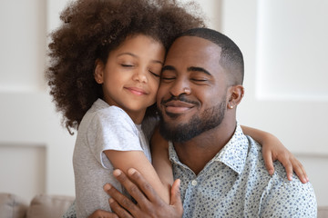 Happy african American dad and daughter cuddle touching cheeks