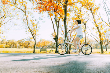 Young woman relaxing and riding bike bicycle in fall autumn park, Bike for fun and healthy