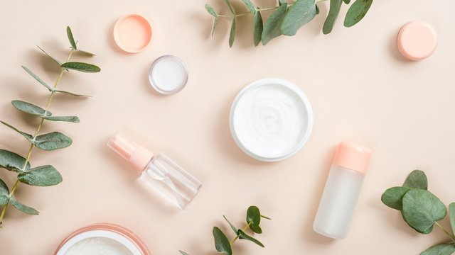 Flat lay composition with natural organic cosmetic products on beige background. Top view hand cream in jar, essential oil, skin lotion and eucalyptus leaves. Natural organic beauty product concept