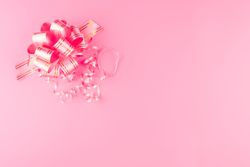 Pink decorative bow for gifts on a pink pastel background.