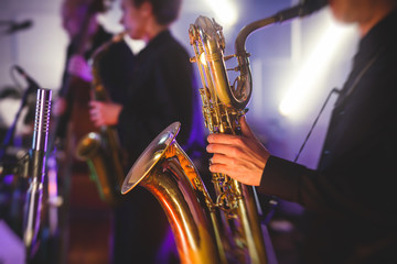 Concert view of a saxophone player with vocalist and musical jazz band in the background