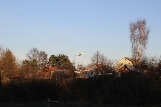 Country autumn landscape with naked trees, village houses, flying avax plan, blue sky
