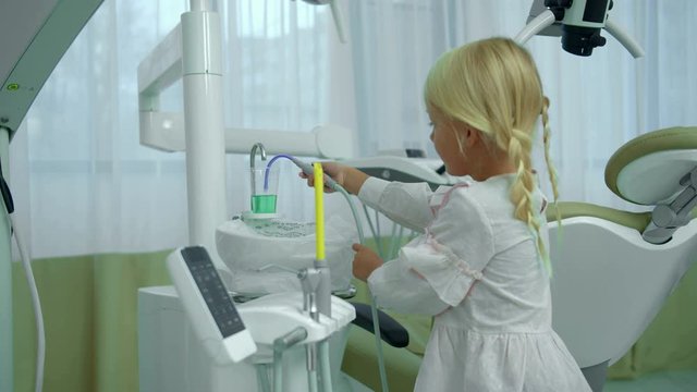 Little girl checks saliva ejector in cabinet