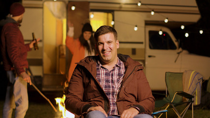 Happy young man sitting on camping chair looking at the camera