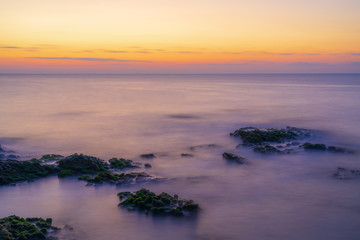 Fototapeta na wymiar Colorful dawn on a rocky seashore, long exposure photography