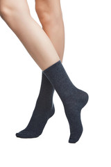 Cropped shot of a girl's cross legs, staying on a white background. It is dark grey socks on her foots. 