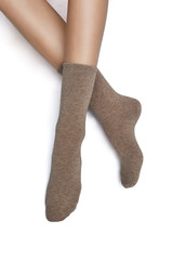Cropped shot of a girl's foots, lying on a white background. It is dark beige socks on her foots. 