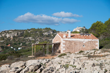 Fototapeta na wymiar Bâtiment isolé sur la côte rocheuse proche de Son Bou, station balnéaire à Alaior, Minorque, îles Baléares