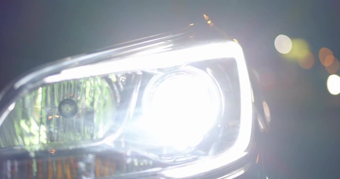 4K - Light of a car headlight on a city street
