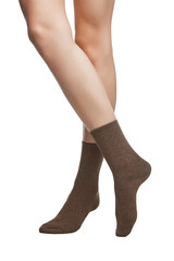 Cropped shot of a girl's cross legs, staying on a white background. It is brown-and-grey socks on her foots. 