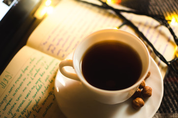 Hot black tea in an irony and warm atmosphere with a garland, a cold winter night and a Christmas atmosphere