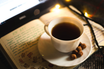 Hot black tea in an irony and warm atmosphere with a garland, a cold winter night and a Christmas atmosphere