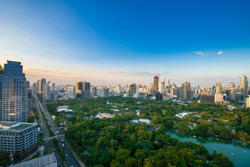 Sightseeing scence of Lumpini park around modern office buildings and condominium in downtown of Bangkok city  with sunset sky clouds