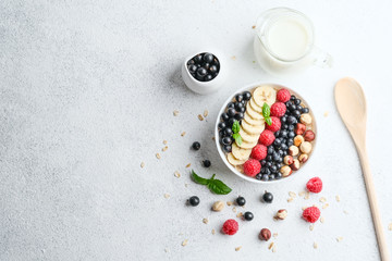 Healthy breakfast. Oatmeal with berries and fruits and milk on a light background top view copy space.