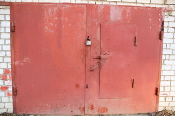 Painted in red color metal garage door with brich wall