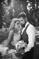 Sensual Black and white foto of bride and groom. Stylish couple of happy newlyweds posing and kisses in the park on their wedding day. Together. The concept of youth, love, fashion and lifestyle. 