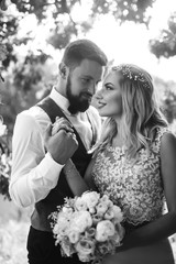 Sensual Black and white foto of bride and groom. Stylish couple of happy newlyweds posing and kisses in the park on their wedding day. Together. The concept of youth, love, fashion and lifestyle. 