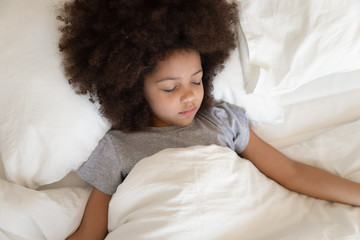 Top view of calm biracial girl sleeping in comfortable bed