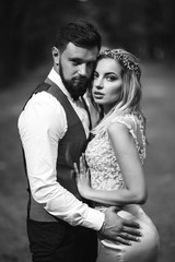 Sensual Black and white foto of bride and groom. Stylish couple of happy newlyweds posing and kisses in the park on their wedding day. Together. The concept of youth, love, fashion and lifestyle. 