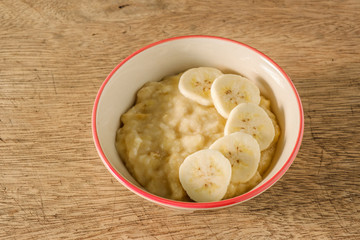 Mashed bananas in bowl on woodden backdrop