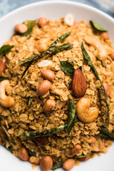 Oats Chivda / Chiwda is a healthy indian recipe with added chilli, peanuts, cashew, almond and curry leaf for flavour. Selective focus