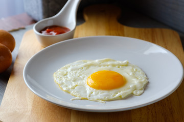 Close up  fried egg is in a white round dish placed