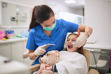 Dentist woman examining tooth patient at dental procedure.