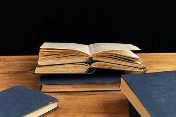 Old books lie on a wooden table.