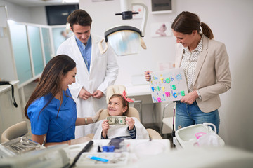 Loss baby teeth. dentist examining his girl patient in dentist’s