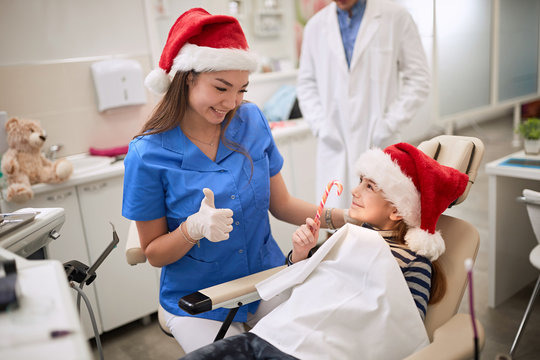 Dentist woman in Santa hat examining tooth patient in ambulant.
