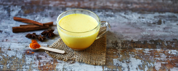 Turmeric milk with spices in a mug. Golden turmeric milk. Indian health drink. Selective focus. Macro.